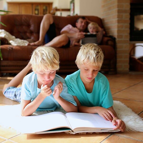 Two brothers reading on tile flooring